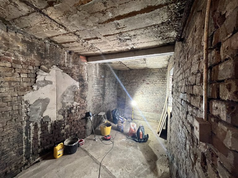 Underground room with exposed brick walls, a beam across the soffit and equipment on the floor. Underground room with exposed brick walls, a beam across the soffit and equipment on the floor.