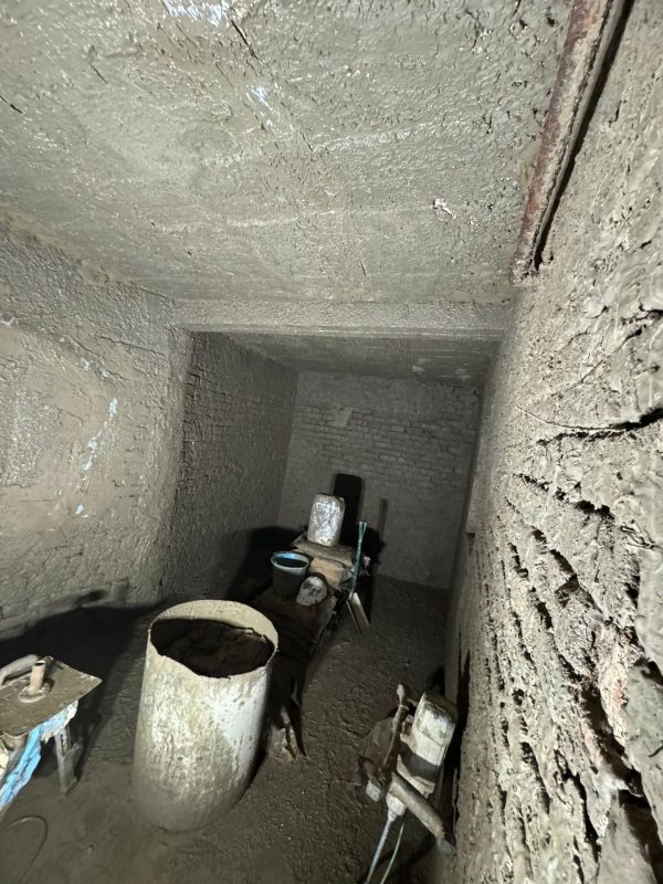 Rough grey material on walls and soffit, with buckets and tools in the room. Rough grey material on walls and soffit, with buckets and tools in the room.
